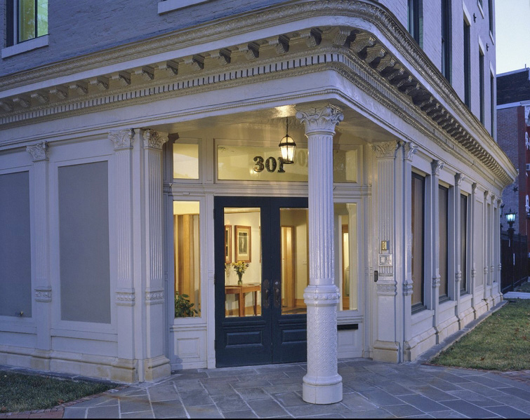 Corner entrance of a warm decorated space of federalist-revival style building at dusk