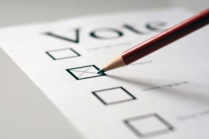 Stock image of a red pencil marking a paper ballot with an 'x'.