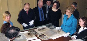 A crowd of people looking at photos placed on a table