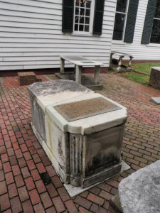 Rectangular marble monument with a text plaque in a brick courtyard