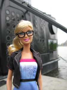 Barbie doll with thick black rim glasses and a black blazer