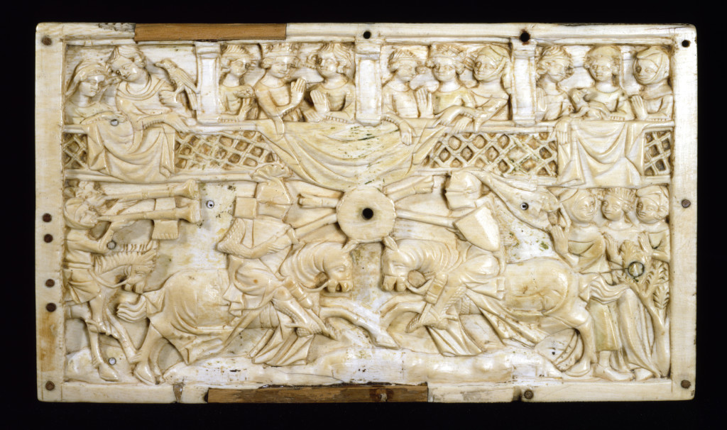 Carved ivory scene of two horseback jousters with a crowd above watching.