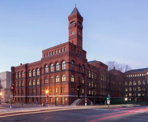 Large brick-colored building with 5 stories and a narrow tower