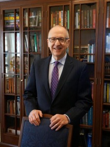 Dr Skorton poses in front of a dark wood bookcase