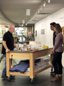 Three people stand around a table filled with materials used in frame conservation treatment.