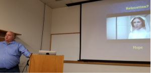 Speaker at a lectern with presentation projected behind