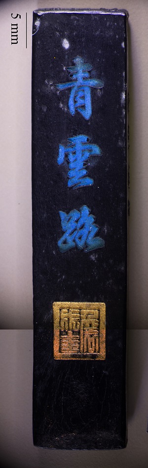 Rectangular black ink stick with blue and gold text.