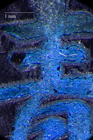 Ink stick with blue character with dimpled texture. Scale at 1 mm