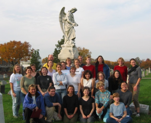 Group posing in front of cemetery statue of an angel.