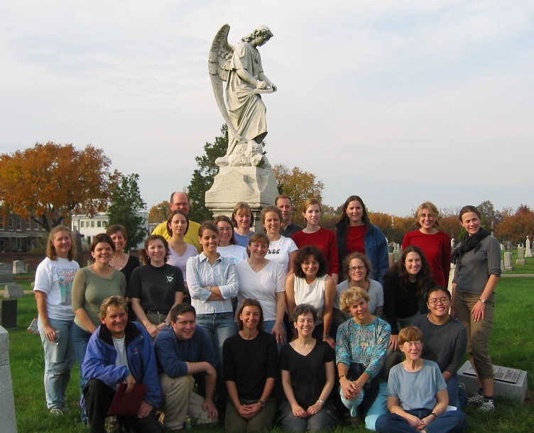Group posing in front of cemetery statue of an angel.