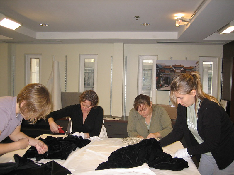 Four women working on textiles laid out on a worktable at the Historical Society of Washington.
