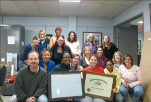 Group portrait with two people holding framed documents at the Charles Sumner School Museum and Archives.