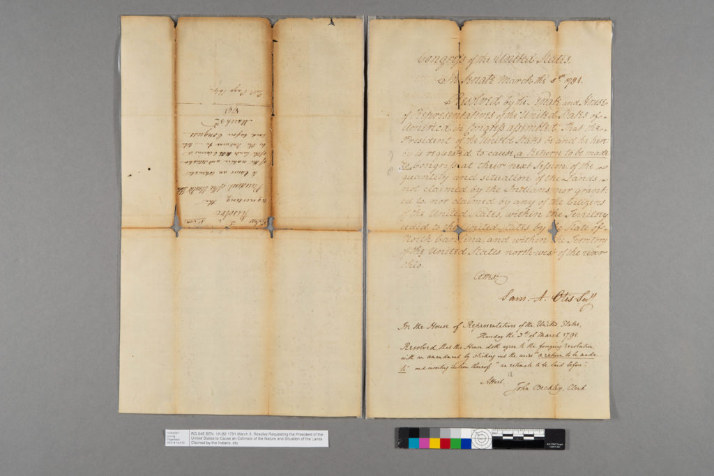 Documentary photography of a historic document with color scale and gray background.