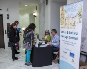 Conservation professionals approach the check-in desk at the 4th Annual Safety and Cultural Heritage Summit, 2019, "Preserving Our Heritage and Protecting Our Health" and are greeted by colleagues.