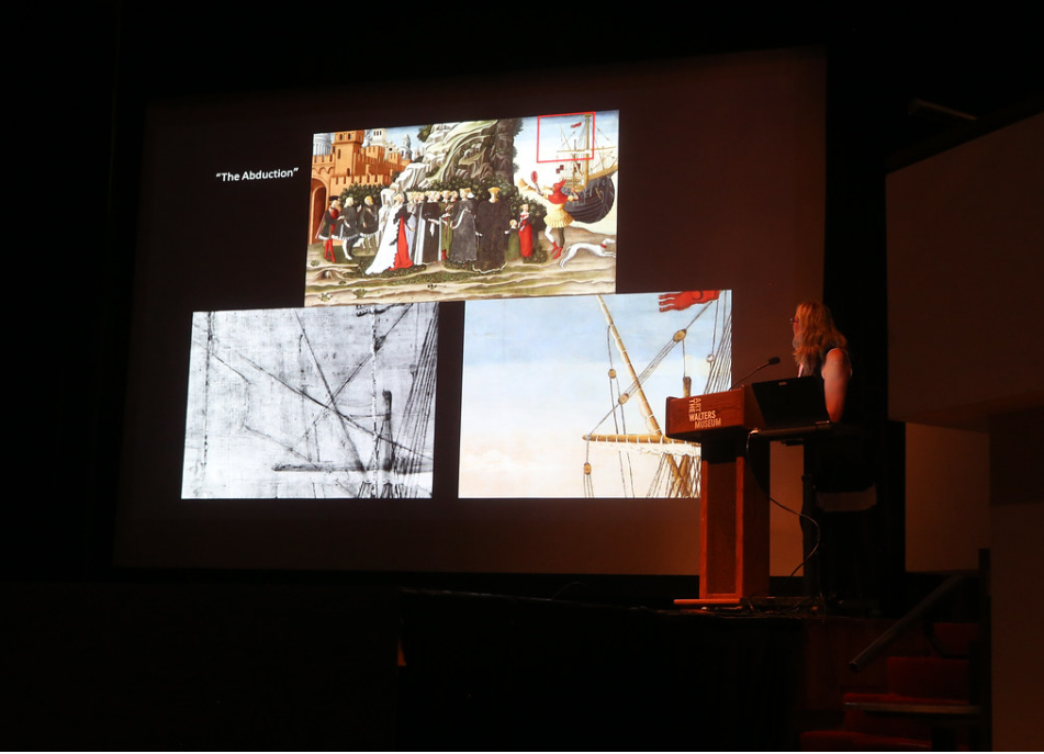 Presenter at a podium in front of slide showing details of an image in visible light and infrared.