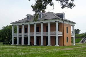 Plantation-style house surrounded by large grass lawn.