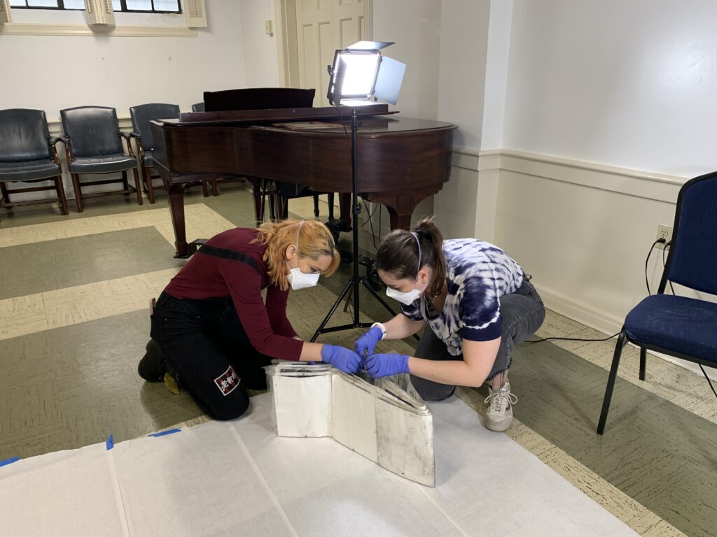 Volunteers in personal protective equipment squatting over a work surface to unfold a triage object