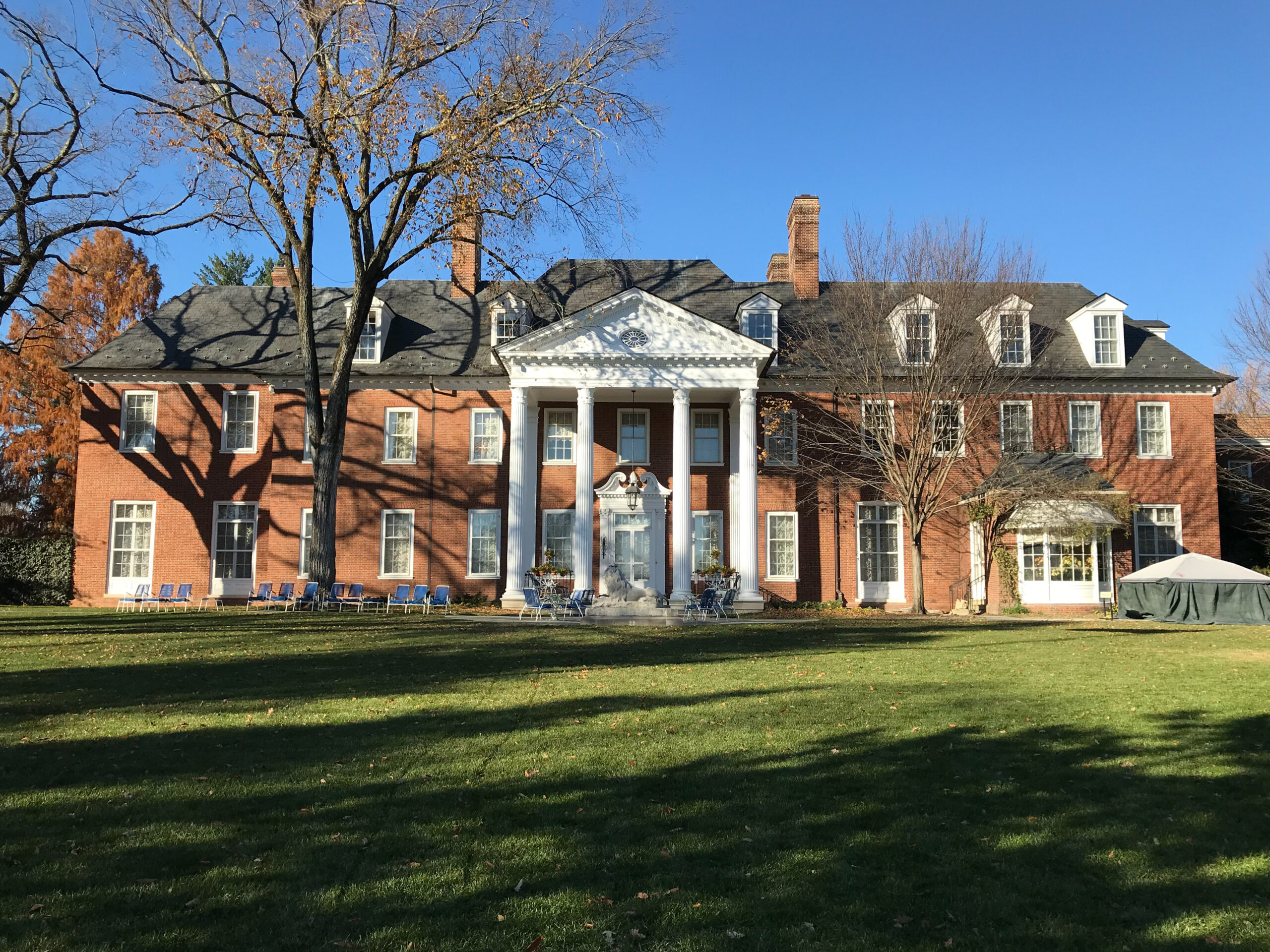 View of large brick manor with grass and trees