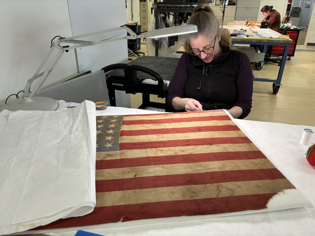 Photo of female conservator treating an American flag