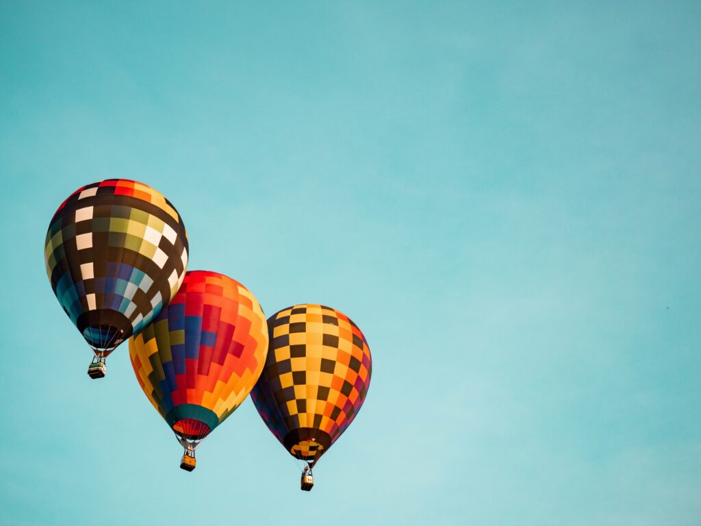 Three hot air balloons in a blue sky.
