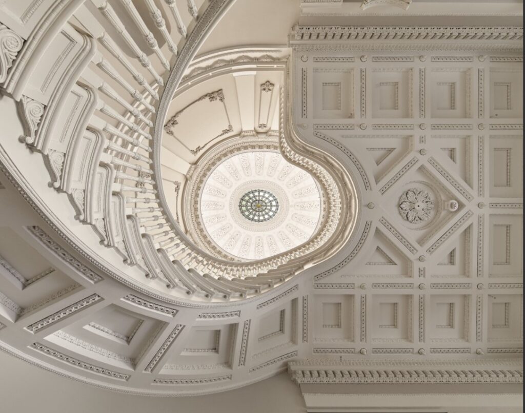 View looking up at staircase and ceiling with decorative moulding